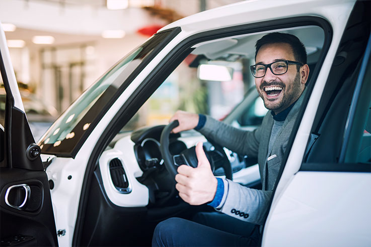 Seguro Auto - Homem sorrindo ao volante do carro